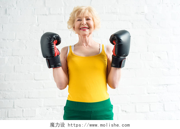 快乐运动的妇女戴着拳击手套快乐运动的资深妇女在拳击手套微笑在照相机